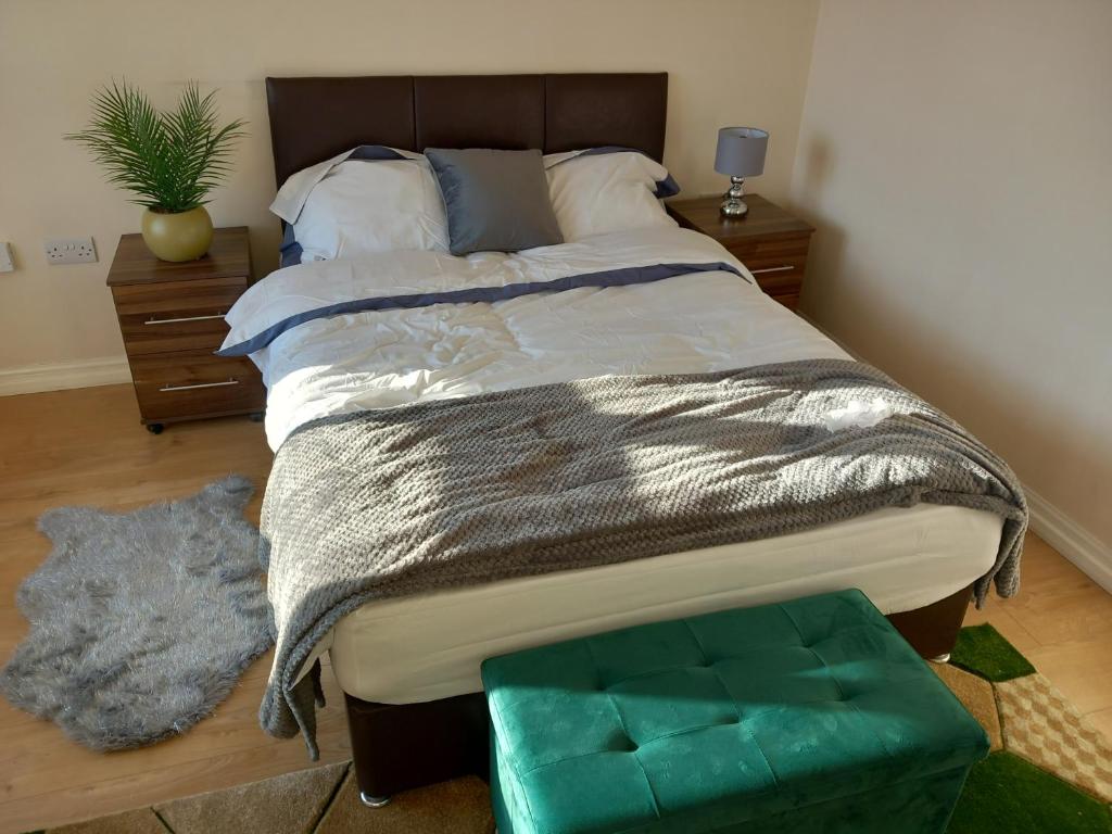 ein Schlafzimmer mit einem großen Bett und einer grünen Ottomane in der Unterkunft Lovely Shared 3 Bed Home Near The Thames in Thamesmead