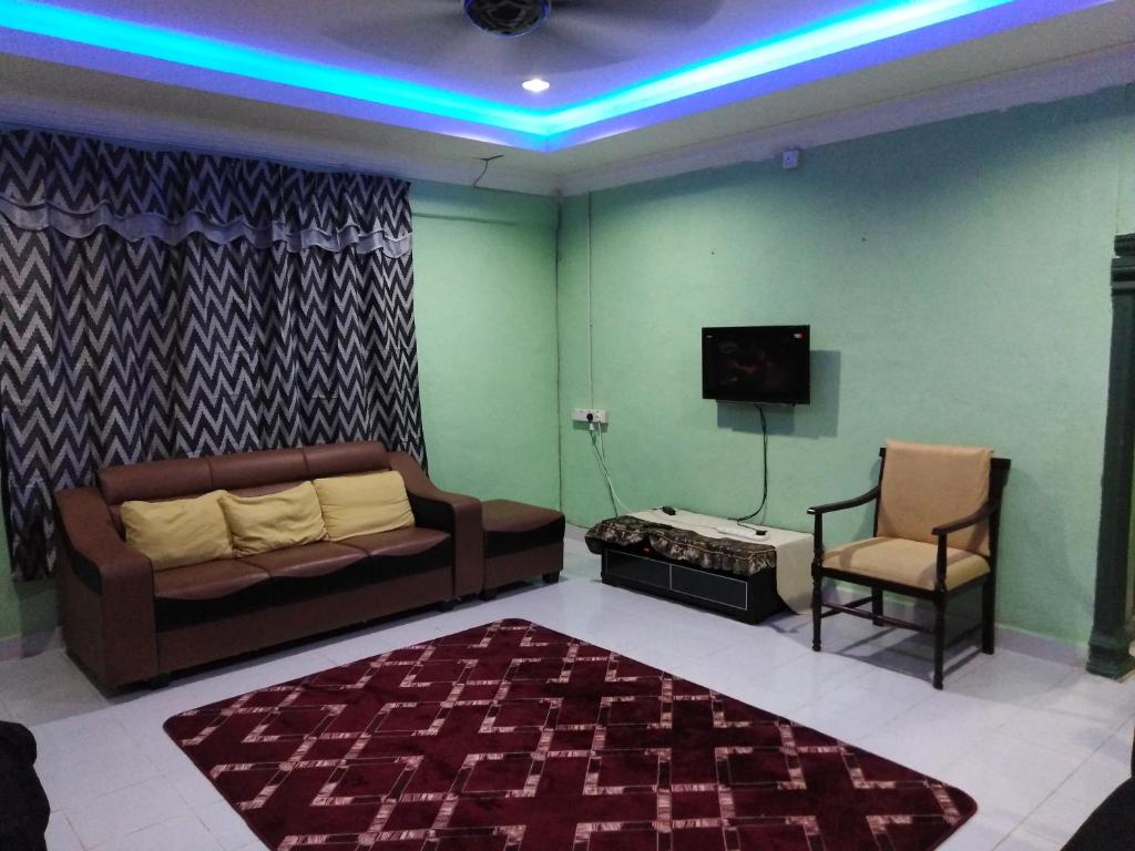 een woonkamer met een bank, een tv en een stoel bij Adeeva Homestay Langkawi in Pantai Cenang