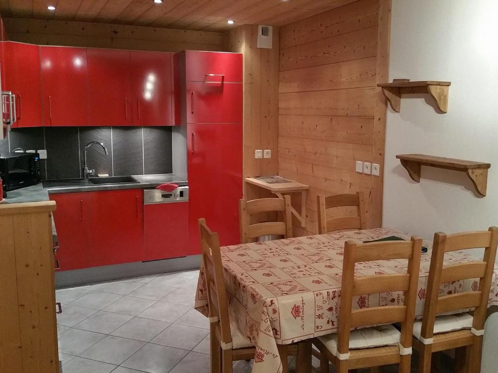 a kitchen with red cabinets and a table and chairs at Appartement Saint-Jean-de-Sixt, 2 pièces, 5 personnes - FR-1-459-113 in Saint-Jean-de-Sixt