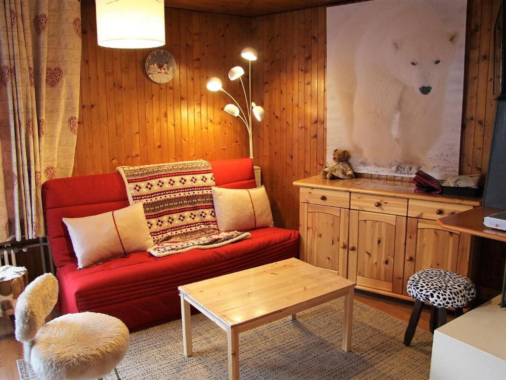 Elle comprend un salon doté d'un canapé rouge et d'une fresque murale représentant un ours polaire. dans l'établissement Appartement T2 Centre Village avec Balcon & Cheminée, Proche Piscine et Pistes - FR-1-459-72, à La Clusaz