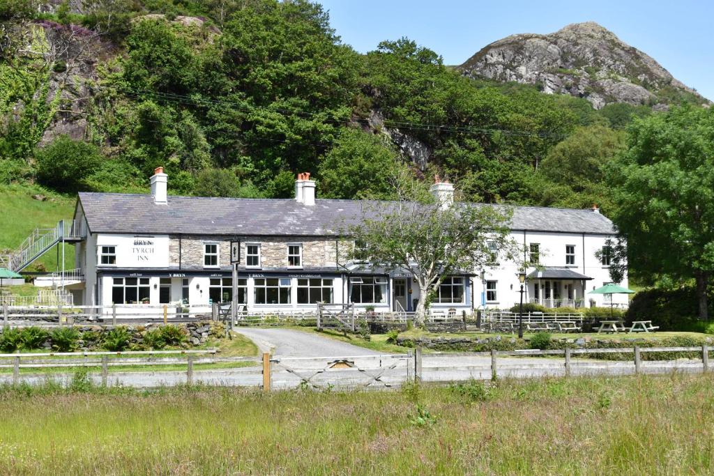 a white house with a mountain in the background at Bryn Tyrch Rooms in Capel Curig