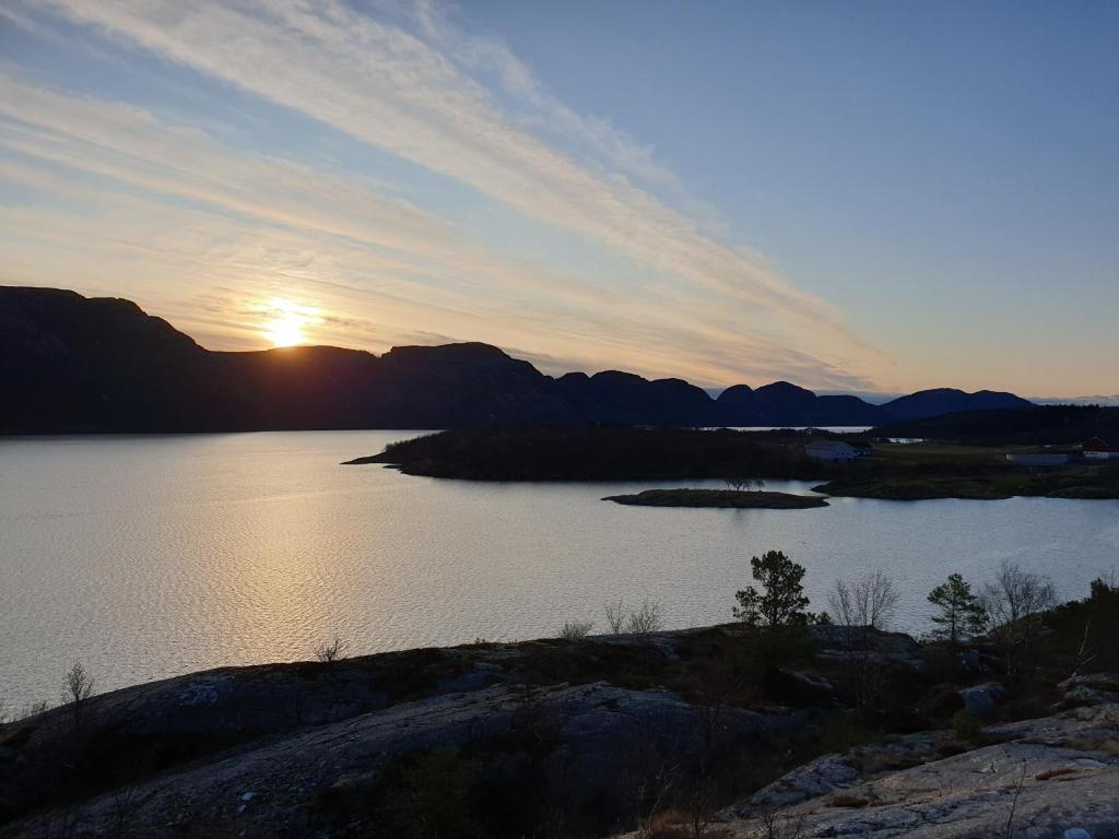 una puesta de sol sobre un cuerpo de agua con montañas en Kleines Haus am Fjord, 