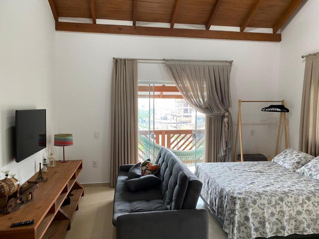 a bedroom with a bed and a couch and a television at Studio Recanto Beach Itapema in Itapema
