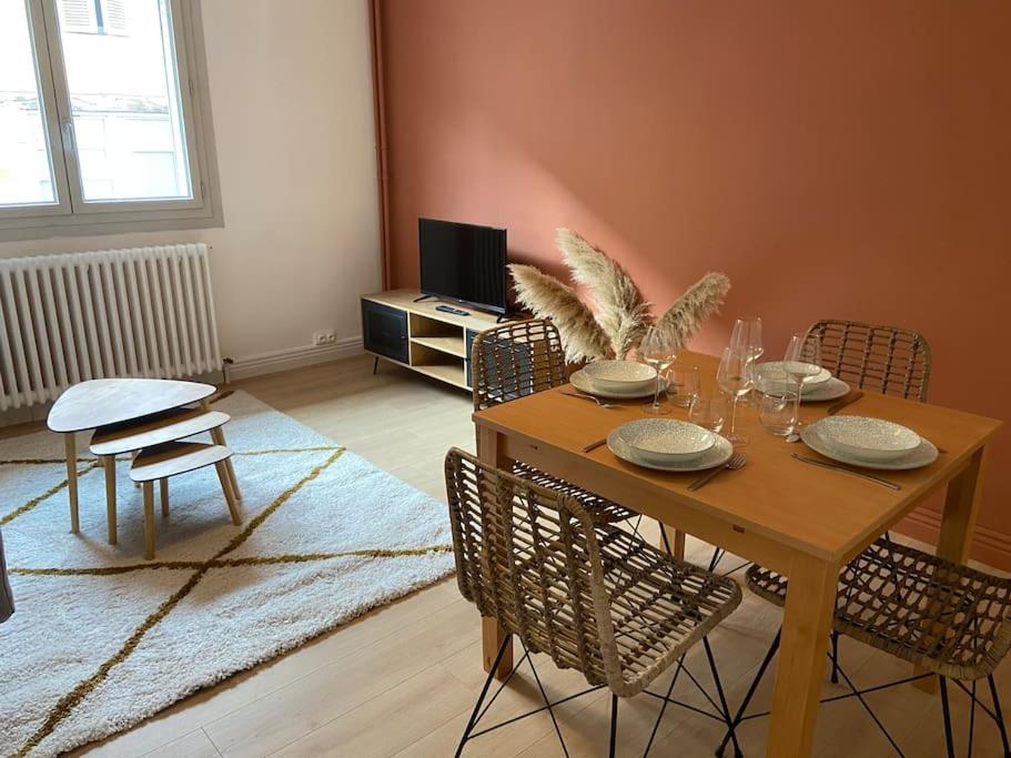 Vaste Appartement Rénové - Centre Ville في بورغ أون بريس: غرفة معيشة مع طاولة وكراسي خشبية