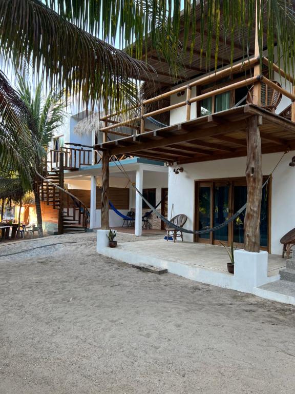 a building with a porch with a bench and palm trees at Cabañas las Palmas Chacahua in Yegüey