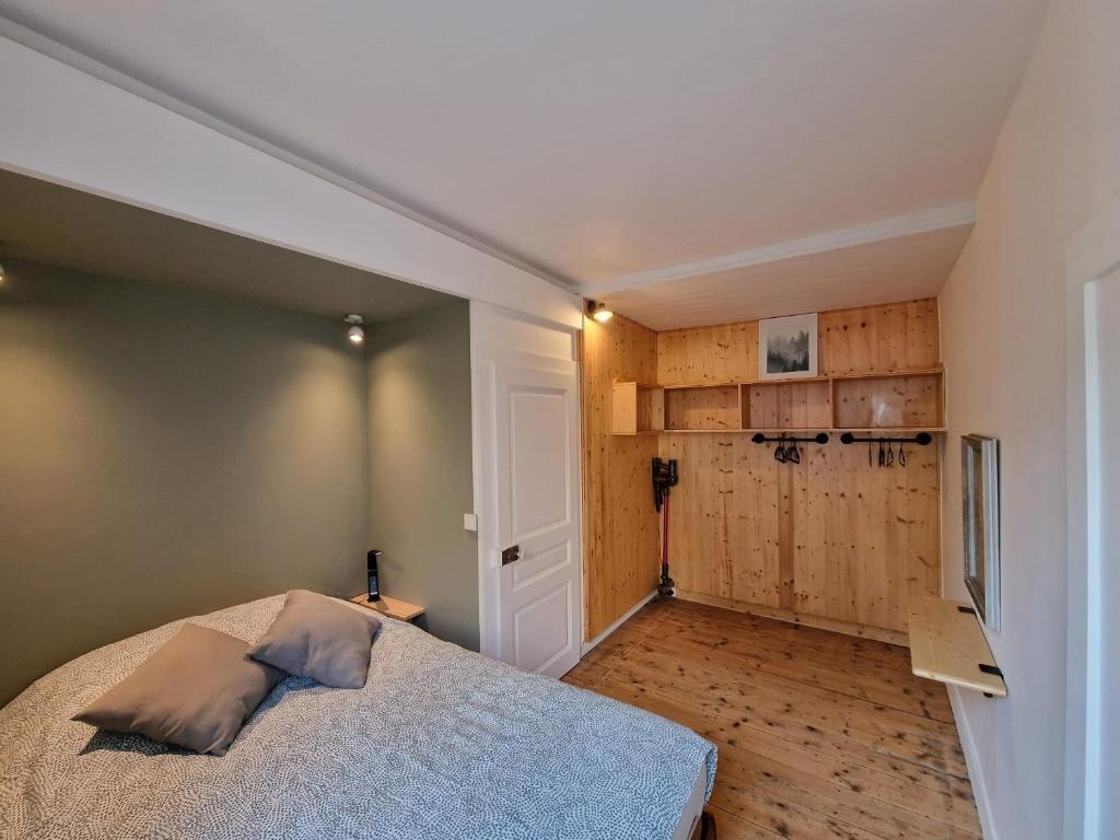 um quarto com uma cama e uma parede com pisos em madeira em Appartement 2/4 pers Le Cosy em Lons-le-Saunier
