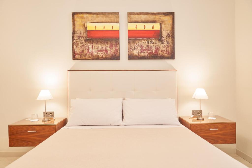 - une chambre avec un lit blanc et 2 tables de chevet dans l'établissement El Hostal de Violeta, à Tomelloso