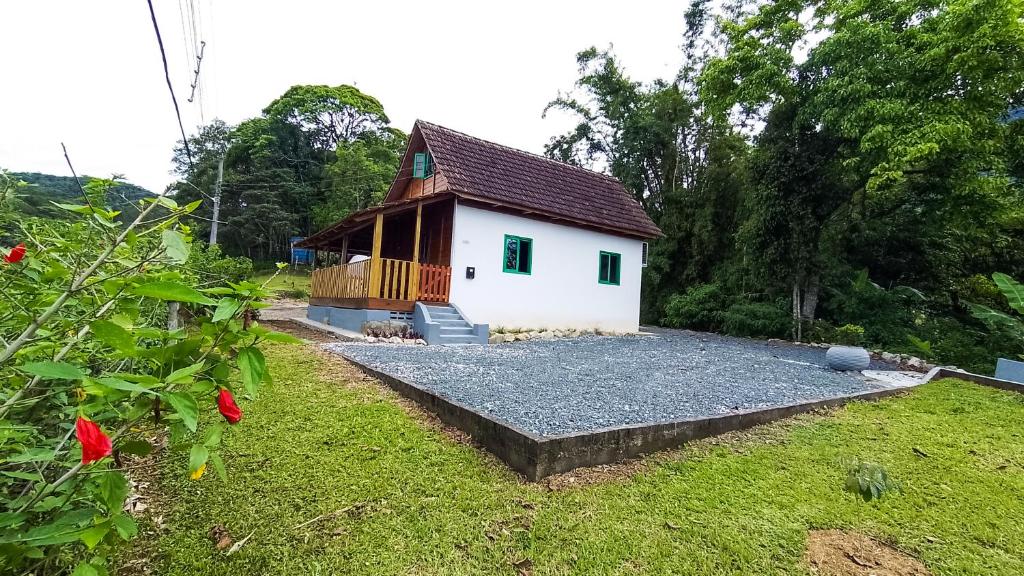 uma pequena casa branca com uma varanda e um quintal em Casa do Tesouro em Joinville