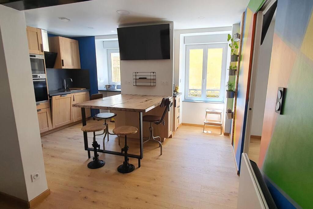 une cuisine avec une table et des chaises dans une pièce dans l'établissement La Perle du Sancy, à La Bourboule