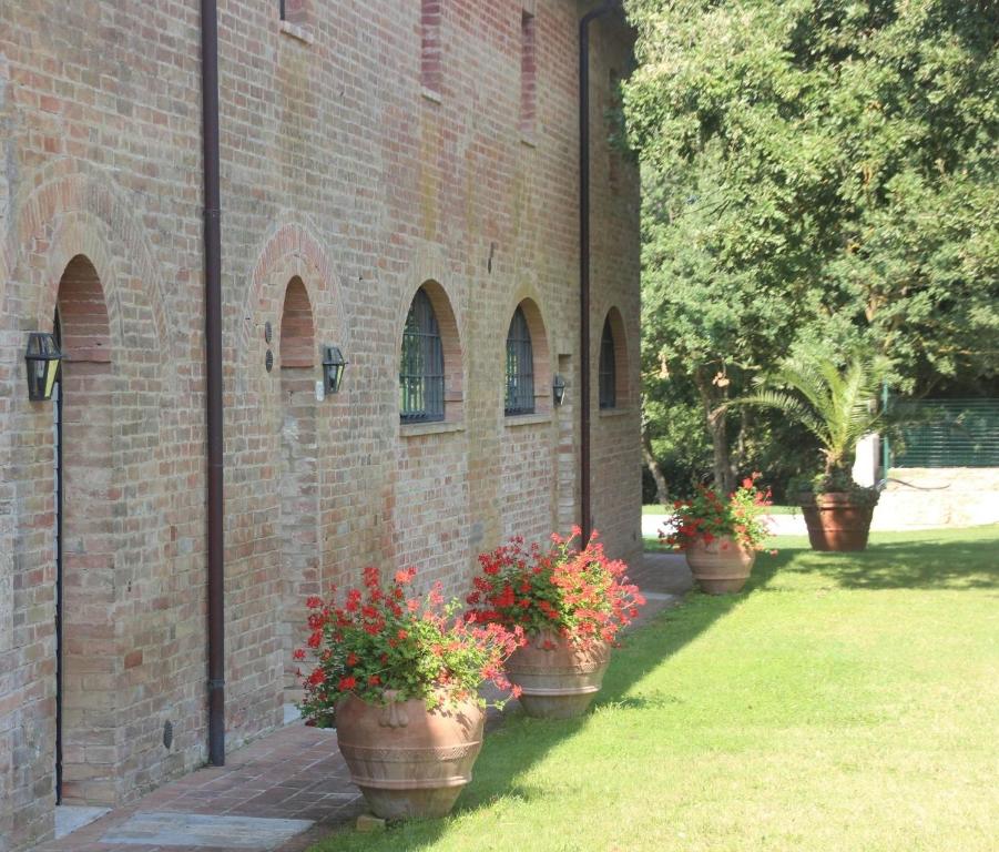 un groupe de plantes en pot sur le côté d'un bâtiment en briques dans l'établissement Podere Ferranino at Ville Ferrano, à San Giovanni dʼAsso