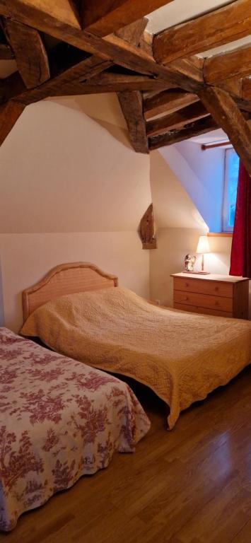two beds in a room with wooden ceilings at Gîte de groupe du Château de la Mézière in Lunay