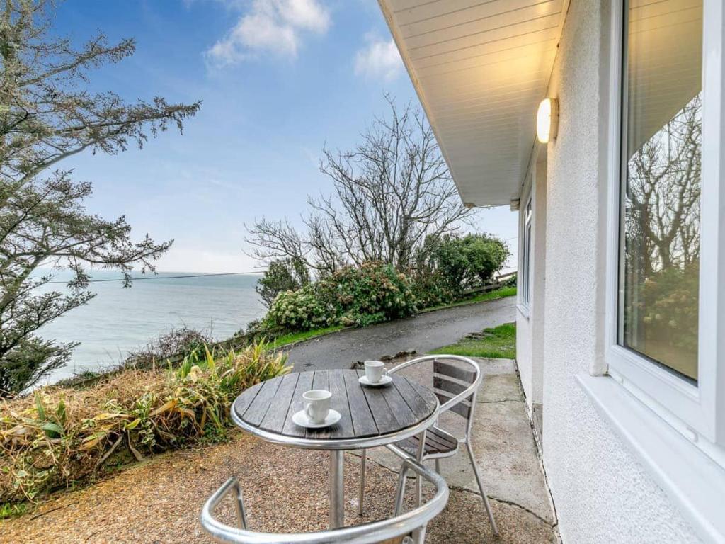 a table and chairs on a balcony with the ocean at Sea Breeze - Mount Brioni in Downderry