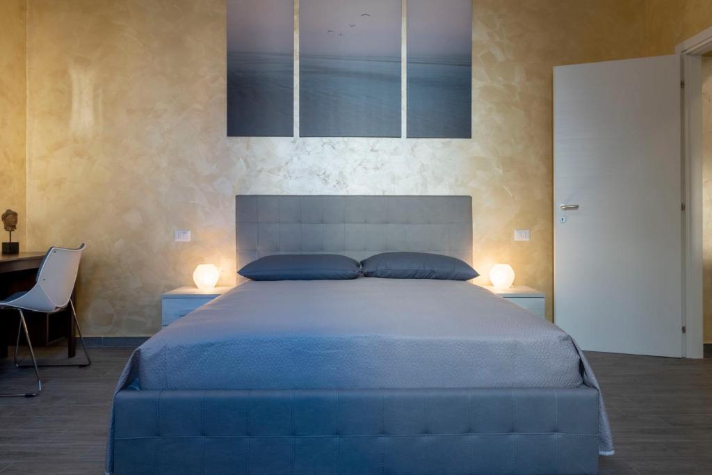 una camera con letto blu, 2 lampade e scrivania di Leader Apartment 1 a Milano