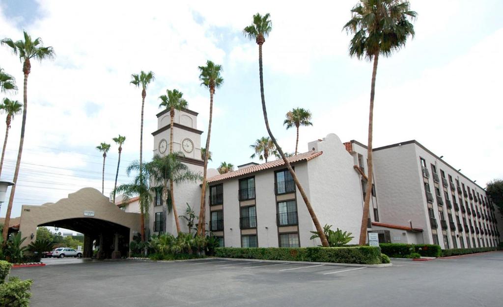 um edifício com uma torre de relógio e palmeiras em Buena Park Grand Hotel & Suites em Buena Park