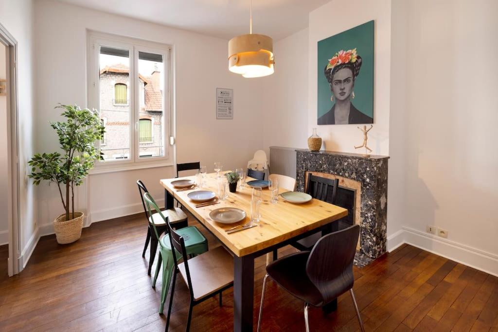 ein Esszimmer mit Tisch und Stühlen und einem Kamin in der Unterkunft Le Familial - Tout équipé - Proche centre in Montluçon