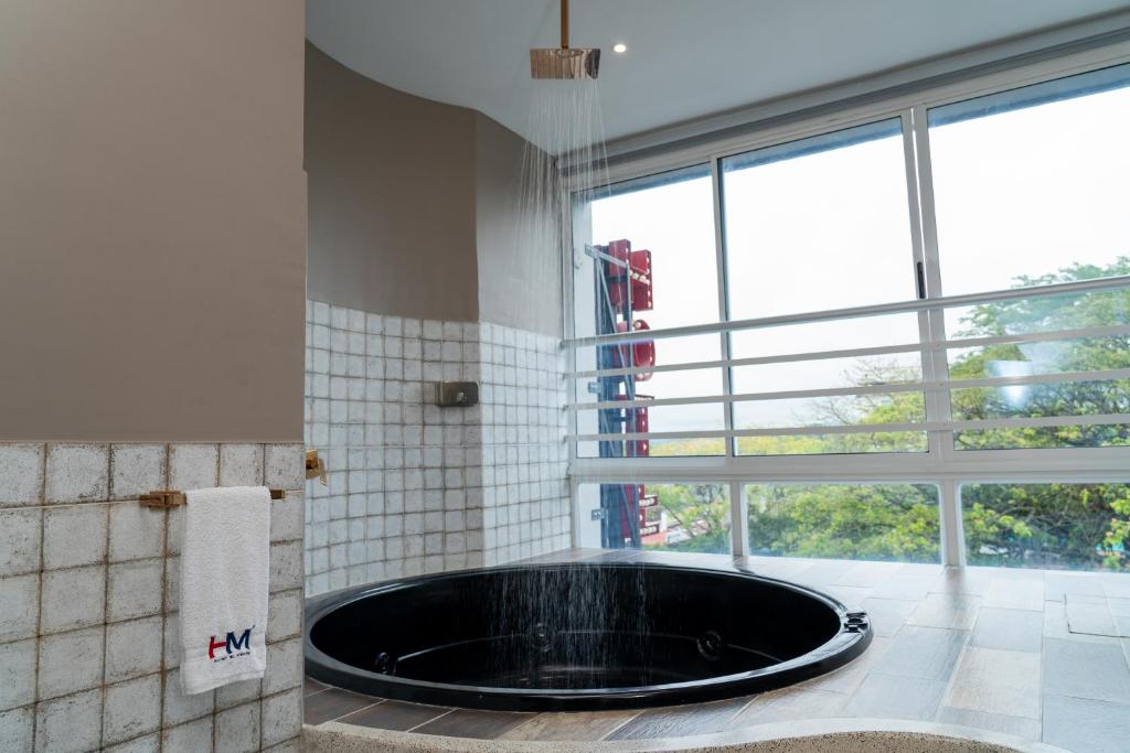 La salle de bains est pourvue d'une baignoire et d'une grande fenêtre. dans l'établissement Hotel El Meson, à La Dorada