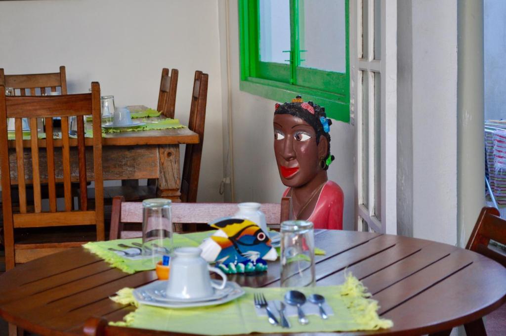 a woman sitting at a table with a mask on it at Pousada Casa das Rosas in Búzios