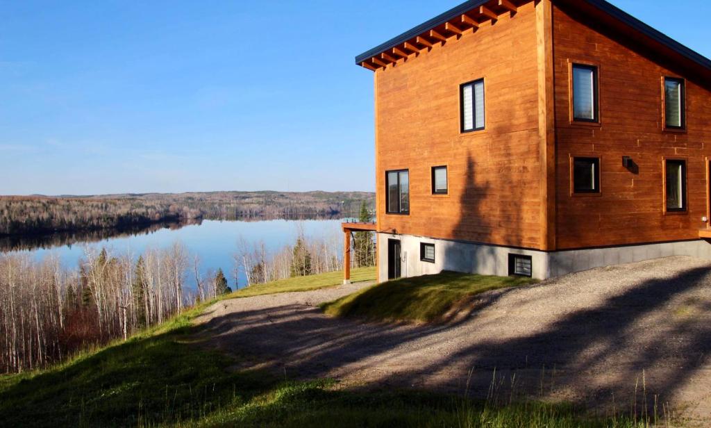 a brick building on top of a hill next to a lake at Chalets domaine Otis in Saint-Félix-d'Otis
