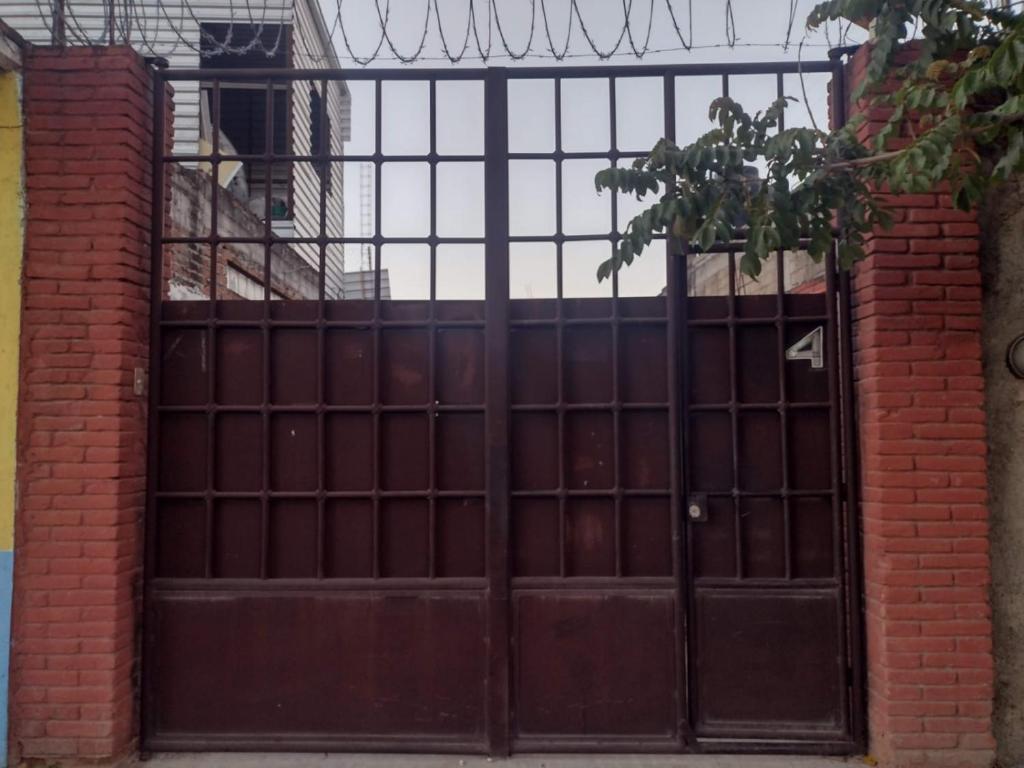 an iron gate with a door with a brick wall at Casa Framboyan in Santa María Azompa