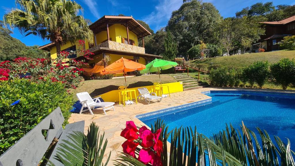 a house with a swimming pool with chairs and umbrellas at Piscina Climatizada em condomínio - Atibaia SP in Atibaia