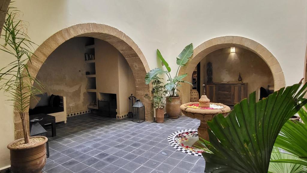 una stanza con tre archi e piante di Riad Dar Nor a Essaouira
