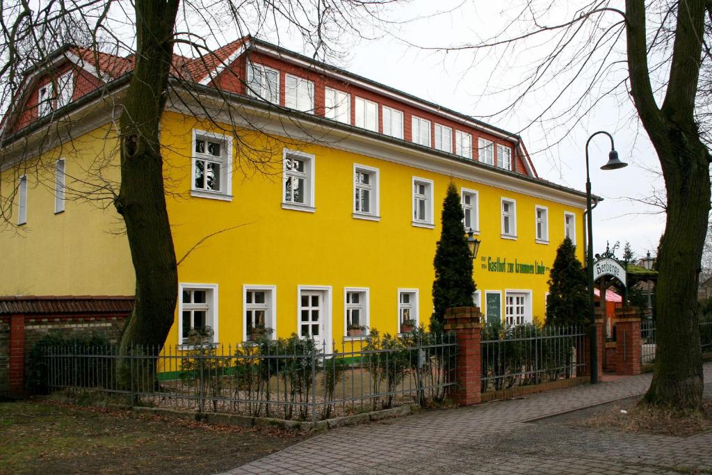 uma casa amarela com uma cerca em frente em Landgasthof zur krummen Linde em Stolpe