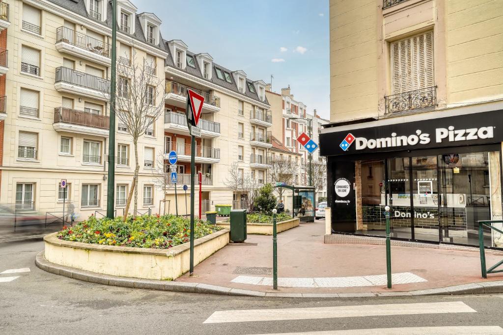 a city street with a dominoes pizza sign in front of buildings at Cozy - Free Parking - 15mn from Paris Montparnasse in Clamart