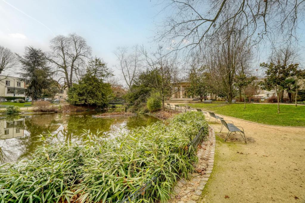 a park with a bench next to a body of water at Cozy - Free Parking - 15mn from Paris Montparnasse in Clamart