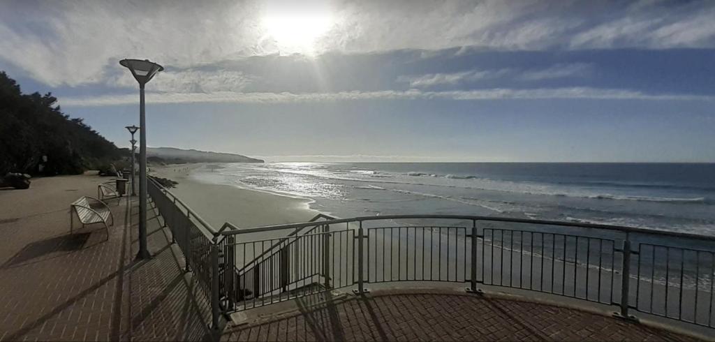 een uitzicht op een strand met een hek en de oceaan bij St Clair Holiday House in Dunedin