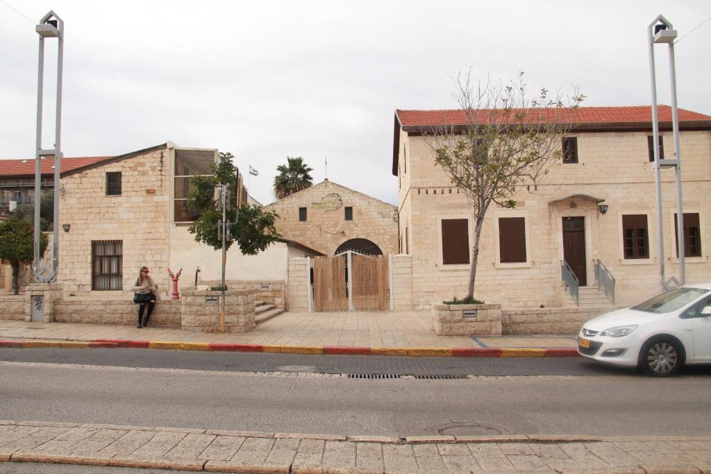 a woman is standing on the sidewalk in front of a building at Al Yakhour Hostel in Haifa