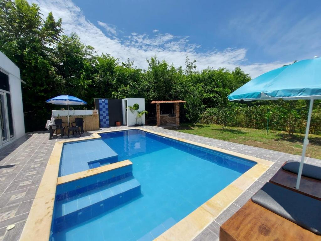 - une piscine avec une terrasse et un parasol dans l'établissement Emuná Campestre, à Carmen de Apicalá