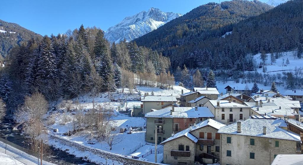 a small town with snow covered buildings and mountains at Appartamento Castellaccio in Ponte di Legno