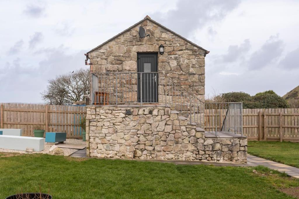 a stone building in a yard with a fence at Cornwall - Unique two storey barn in St Austell