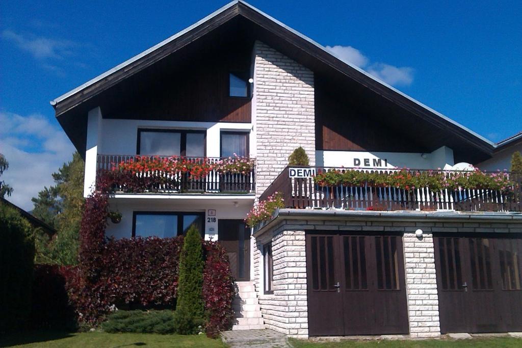 a house with a balcony with flowers on it at Penzion Demi in Stará Lesná