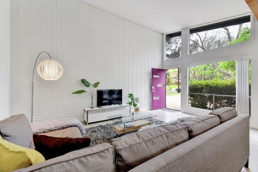 a living room with a couch and a tv at Sunny Mid Century Modern with Parking Patio and Fenced Yard by Lodgewell in Austin