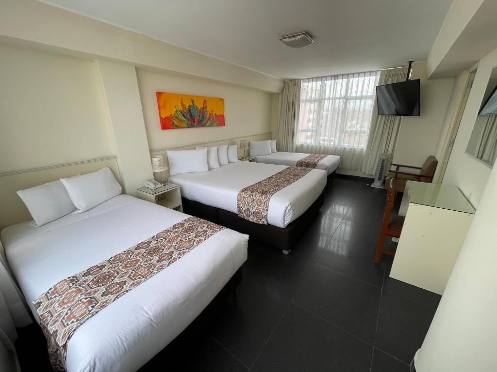 a hotel room with two beds and a television at Hotel Premier in Tacna