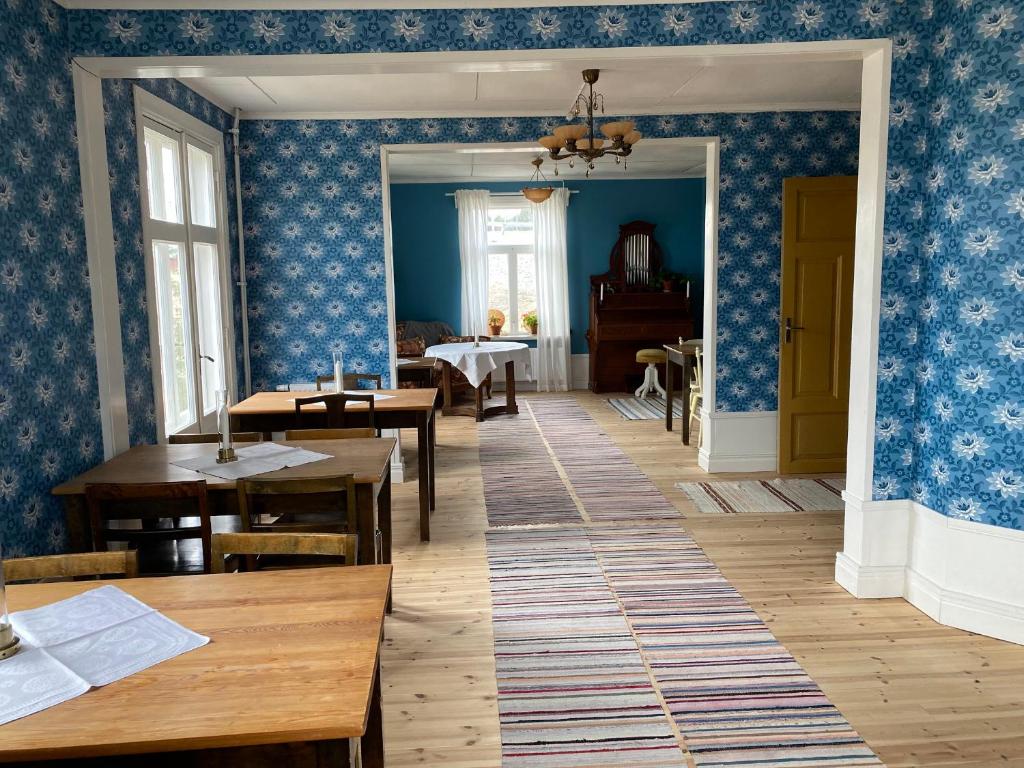 comedor con paredes azules y mesas de madera en Strandgården Hoverberg., en Svenstavik