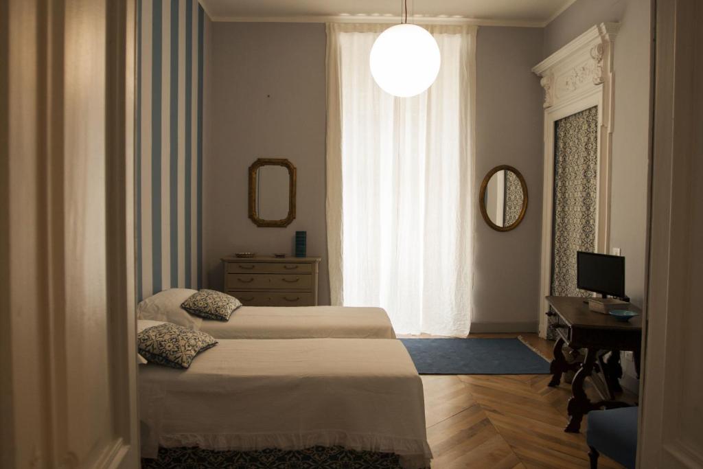 a bedroom with two beds and a desk and a window at Palazzo Bellini in Turin