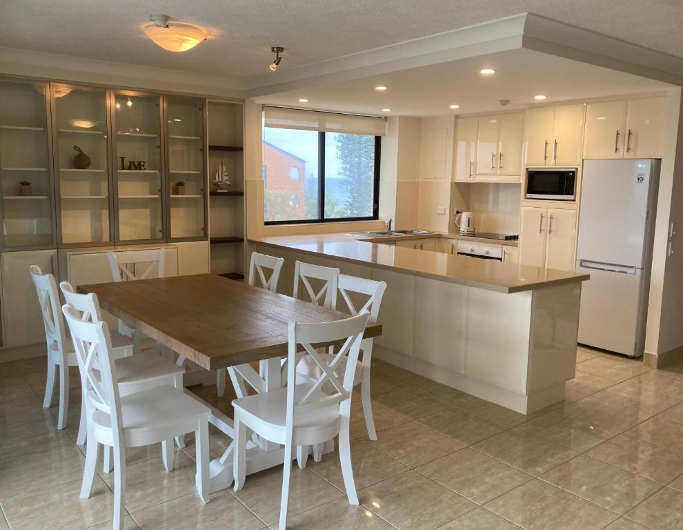 a kitchen with a wooden table and white appliances at Burgess @ Kings Beach Apartments in Caloundra