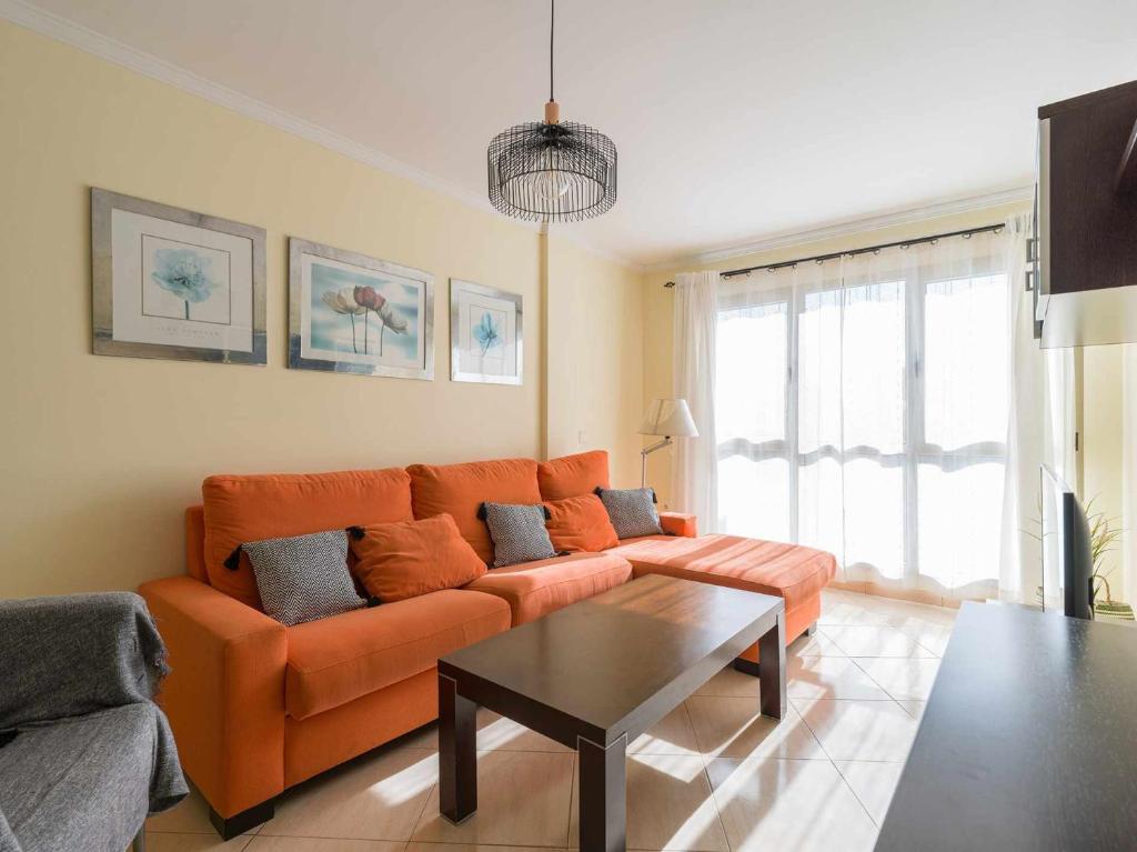 uma sala de estar com um sofá laranja e uma mesa em Mahostly Apartamento Castillo em Puerto del Rosario