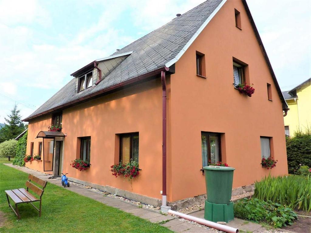 una casa grande de color naranja con un banco delante en Chalupa u Procházků en Meziměstí