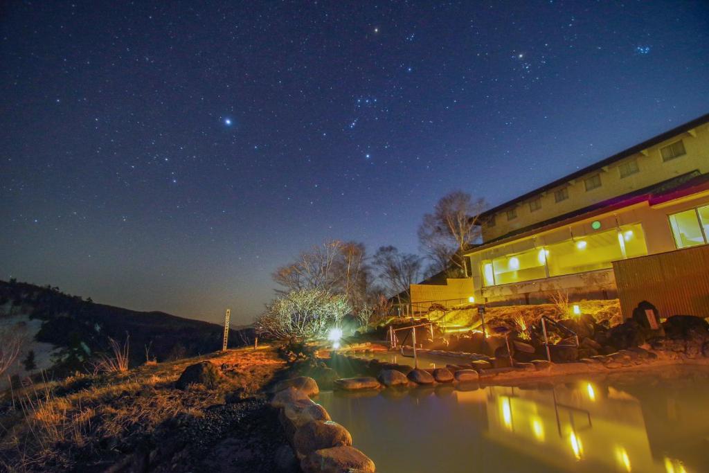 un edificio con un río delante de él por la noche en Manza Prince Hotel, en Tsumagoi