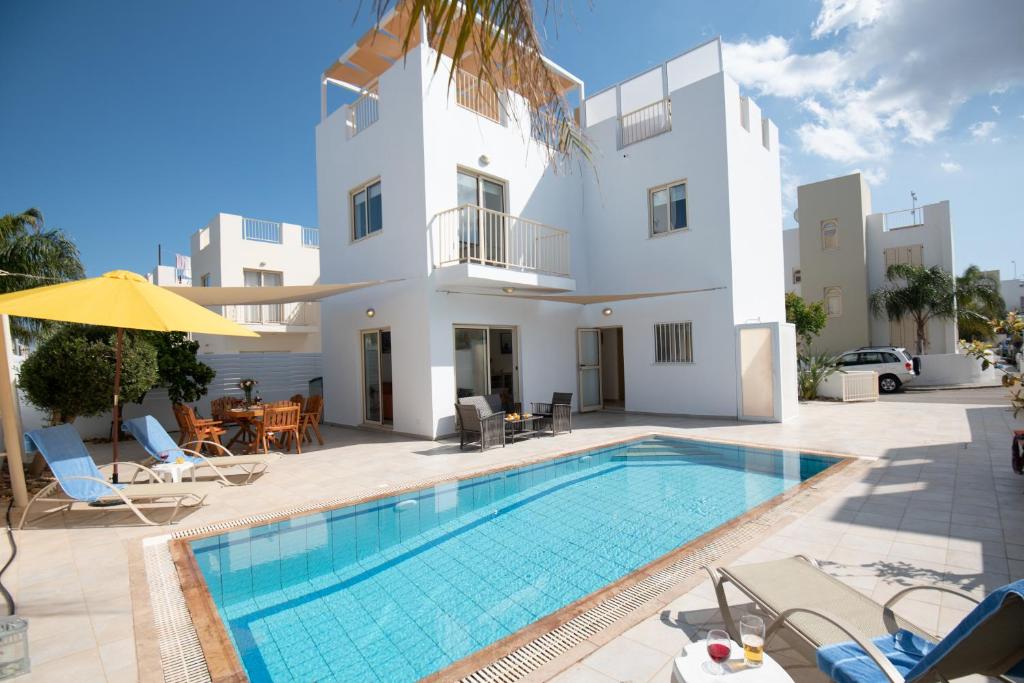 a villa with a swimming pool in front of a house at Villa Pomelo in Protaras