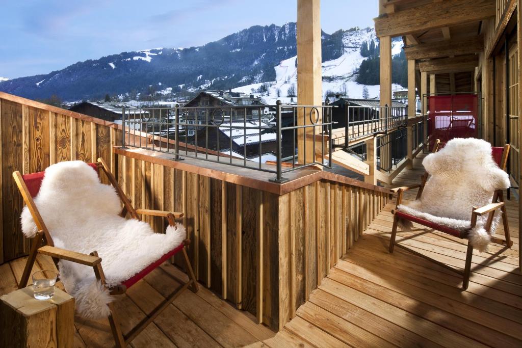 two chairs sitting on a deck with snow covered mountains at Kitzhof Mountain Design Resort in Kitzbühel