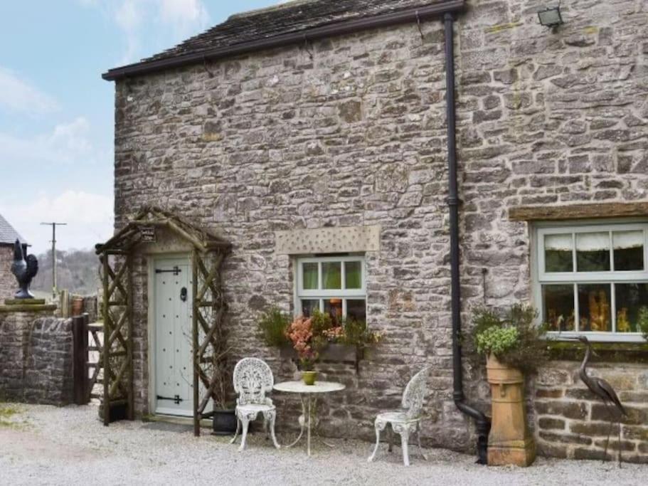 una casa de piedra con una mesa y sillas delante de ella en Sweet knoll cottage, en Buxton