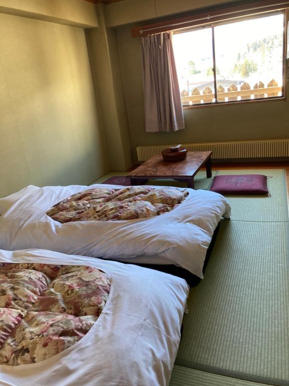 a room with three beds and a table and a window at Resort Inn Seikan in Hakuba