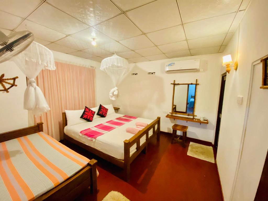 Dormitorio pequeño con cama y espejo en Sheran Safari House en Udawalawe