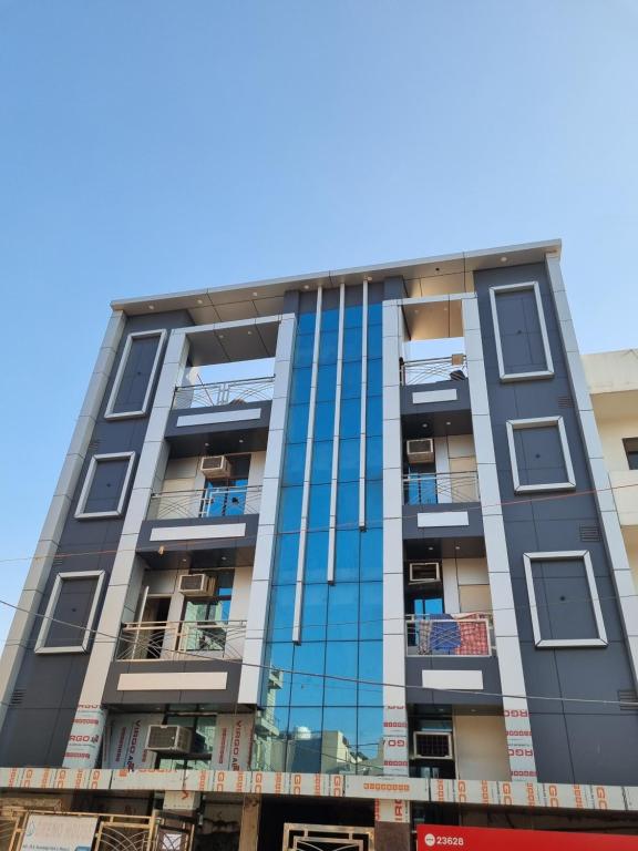 a tall apartment building with blue glass windows at Greno House in Greater Noida