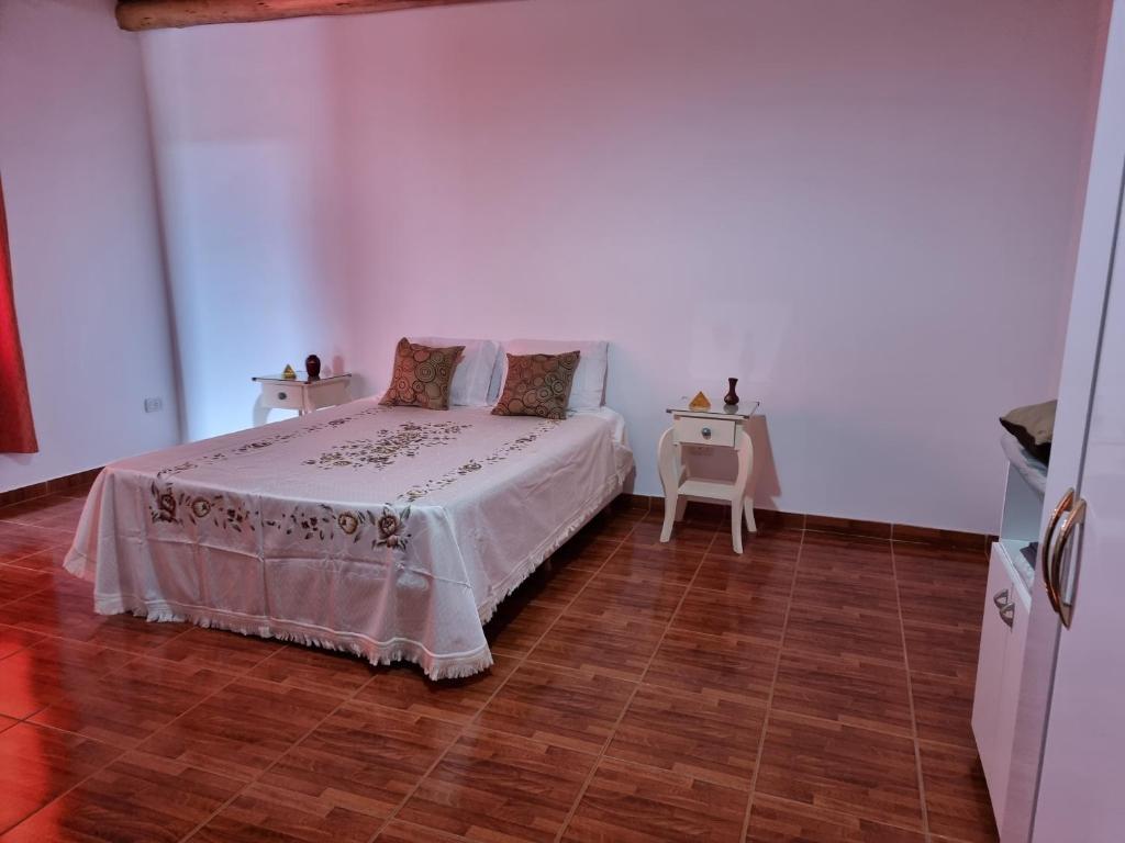 1 dormitorio blanco con 1 cama y 2 mesas en Departamento Tunuyán en Tunuyán