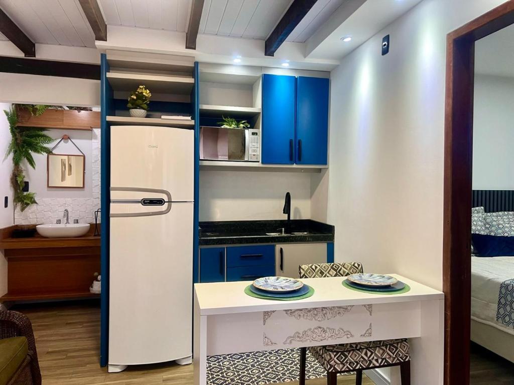 uma pequena cozinha com armários azuis e um frigorífico branco em Mar Rio casa de praia em Piçarras